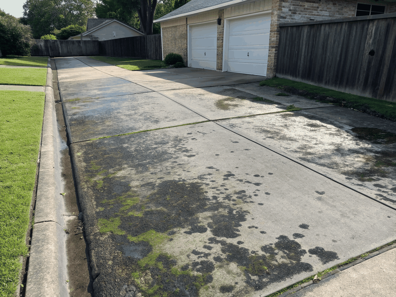 Dark blackened concrete driveway before deep surface pressure wash