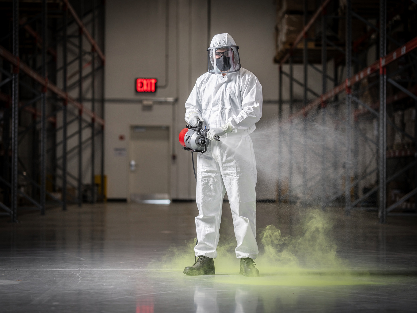 Certified pest control technician in full protective coveralls and respirator applying an indoor misting treatment inside an Auckland home